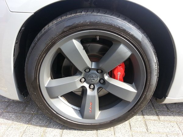 Graue Alufelge mit roter Bremszange nach der Reinigung