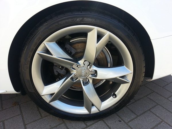 Silberne Alufelge an einem weißen Fahrzeug nach der Pflege