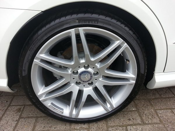 Silberne Felge an einem weißen Fahrzeug nach der Felgenreinigung